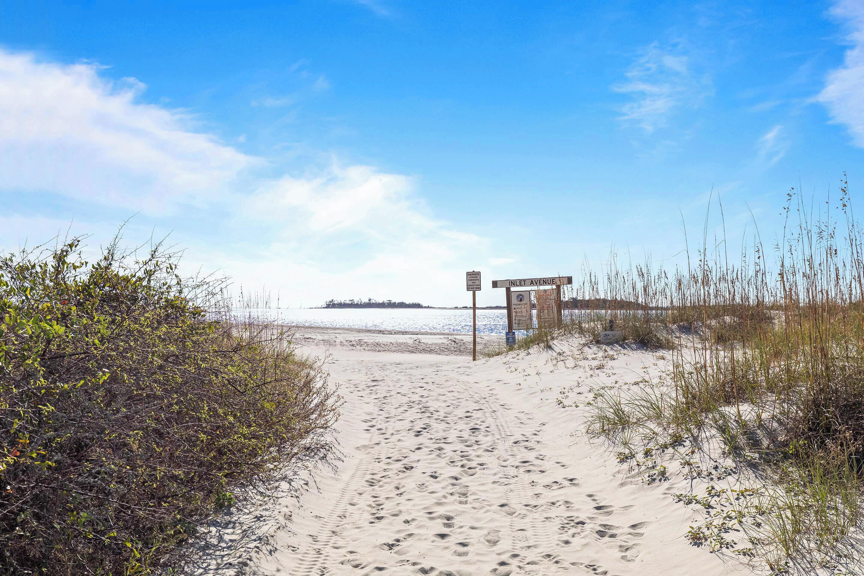 A sandy beach path leading to a structure labeled "INLET AVENUE" with a view of the ocean in the background.