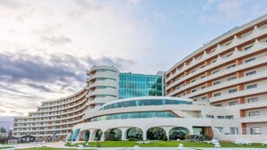 Un hôtel moderne à la façade incurvée, doté de nombreux balcons et d’une entrée principale en verre.
