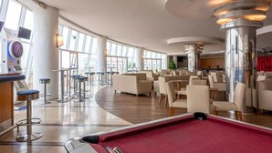 Un espace intérieur vaste et lumineux, doté d’une table de billard, de coins salon et de grandes fenêtres qui laissent entrer la lumière naturelle.