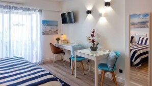 Une chambre d’hôtel avec un lit, un bureau, une chaise, une télévision et une fenêtre avec des rideaux.