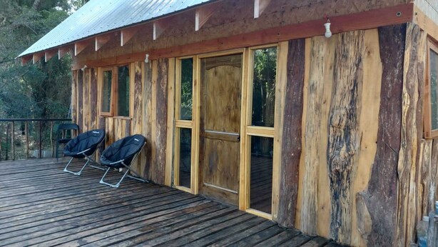 Eine Holzhütte mit großen Fenstern und einer Terrassenfläche.