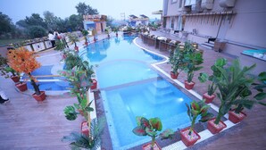 A rooftop pool area with potted plants and a seating area.