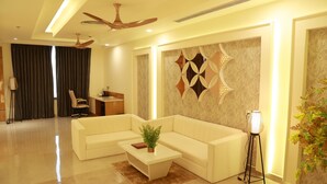A modern living room with a sectional sofa, a coffee table with a plant, a desk with a chair, and a decorative wall piece.
