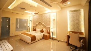 A modern hotel room with a large bed, bedside tables, a desk, and a chair.