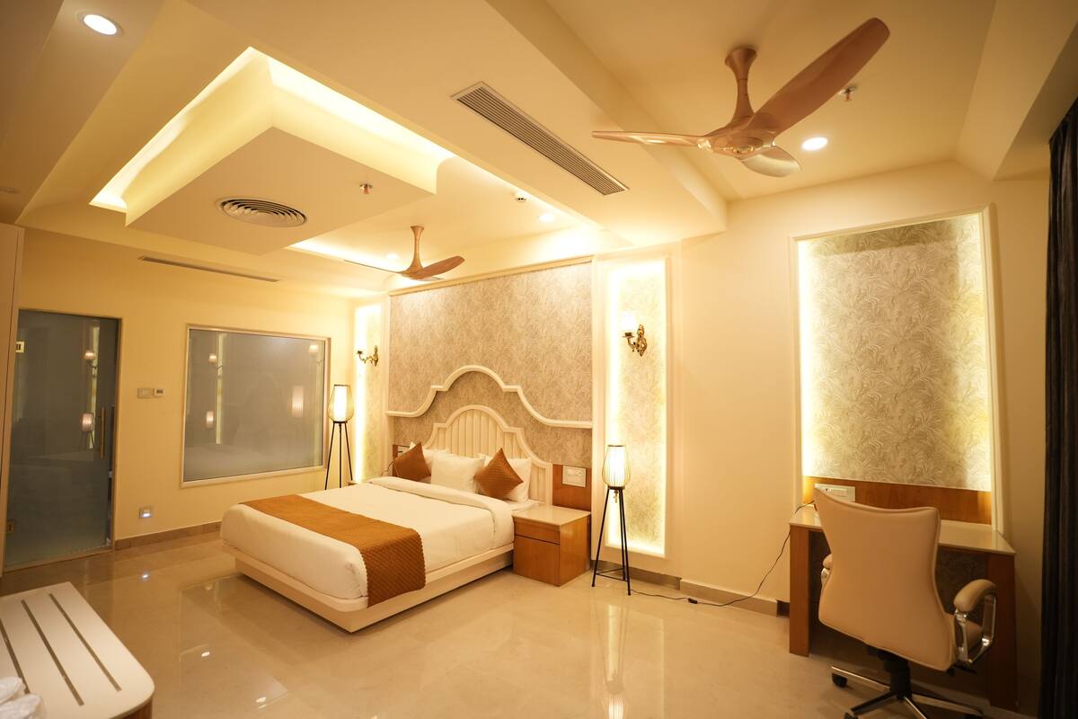 A modern hotel room with a large bed, bedside tables, a desk, and a chair.