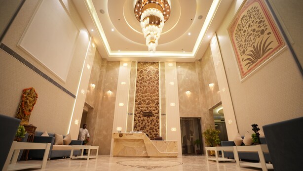 A hotel reception area with a marble floor, a reception desk, and a chandelier.