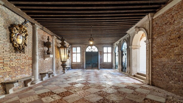 Un couloir doté d’un sol à carreaux, de murs en briques et d’un plafond en bois.