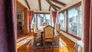 Une salle à manger avec un plafond en bois, de grandes fenêtres et une table dressée pour quatre personnes.