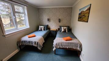 A small, cozy room with two single beds, a nightstand, and a window.