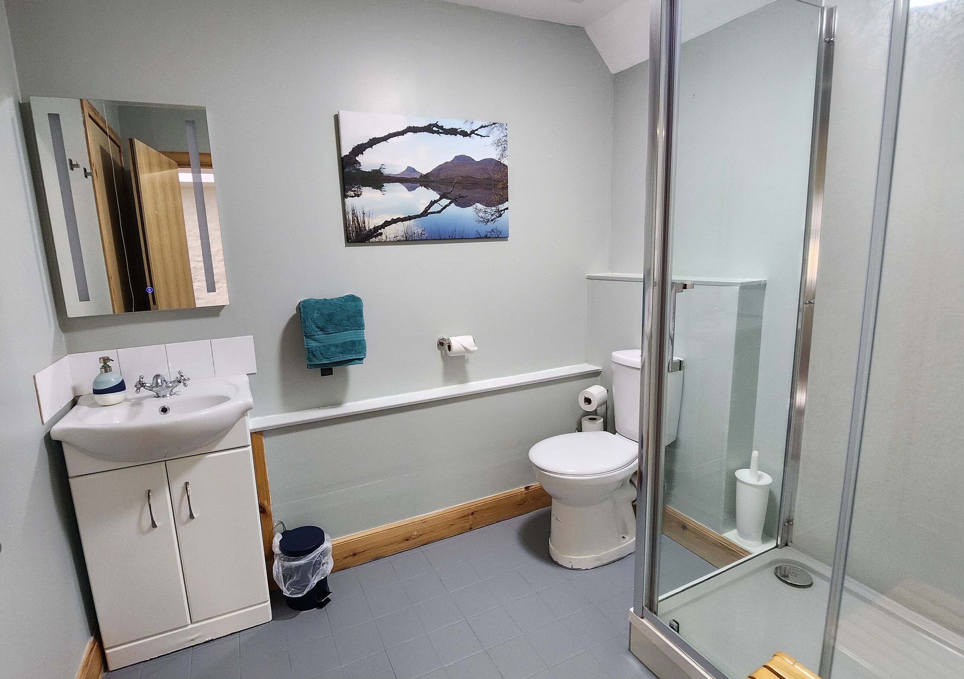 Une salle de bain avec un lavabo blanc, des toilettes et une douche à parois de verre.