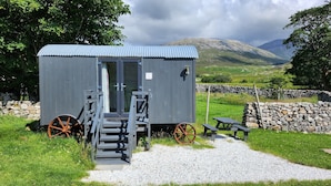 Une petite cabane rustique avec un toit en métal, des marches en bois et une porte.