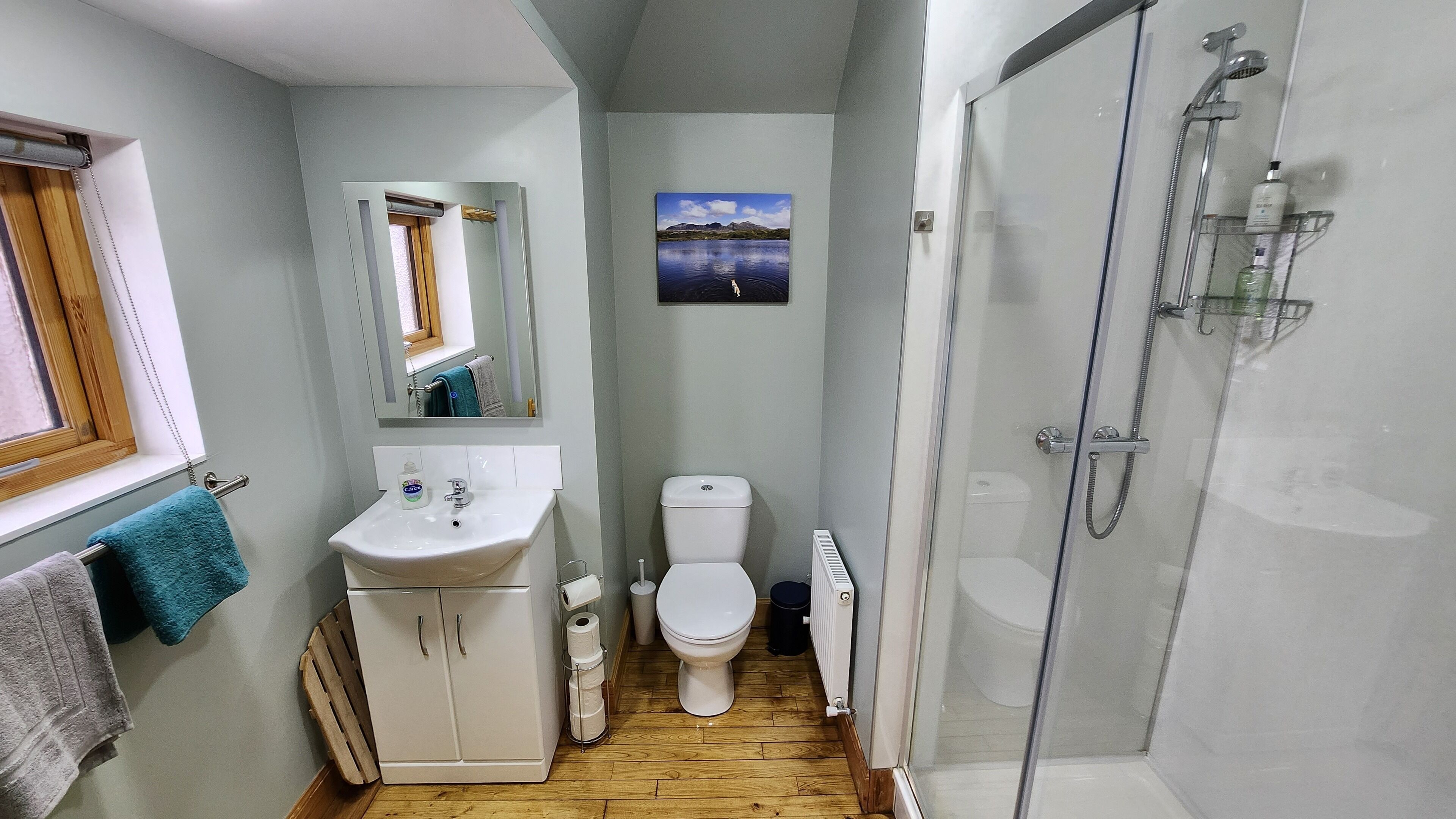Un baño pequeño con lavamanos, inodoro y ducha con mampara de vidrio.