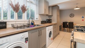Una cocina moderna con lavadora, un lavamanos y una zona de comedor con mesa y sillas.