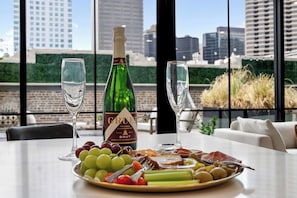 Et bord med en flaske Brut champagne, to glas og en tallerken med forskelligt frugt og oste.