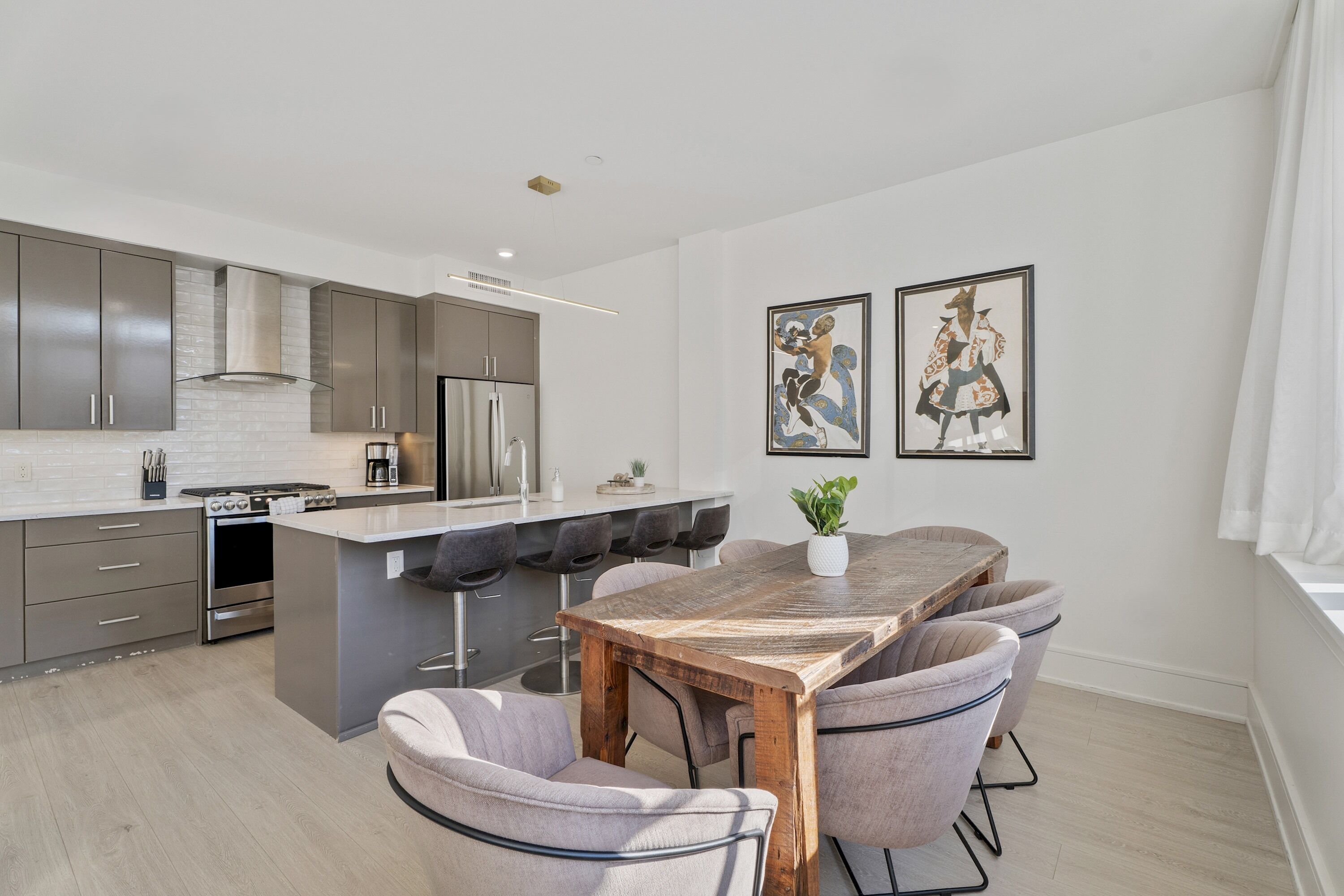 Una cocina moderna con una isla central, taburetes de bar y una mesa de comedor.