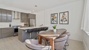 Een moderne keuken met een centraal eiland, barkrukken en een eettafel.