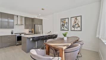 Una cocina moderna con una isla central, taburetes de bar y una mesa de comedor.