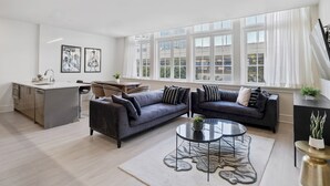 Ein modernes Wohnzimmer mit einer Couch, einem Couchtisch und einer Küchenzeile mit Spüle und Schränken.