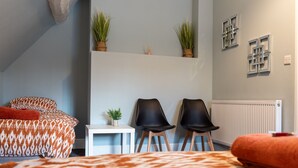 Ein Schlafzimmer mit einem Bett, zwei Stühlen, einem kleinen Tisch und Zimmerpflanzen.