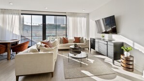 Una sala de estar moderna con sofá, mesa de centro y televisor.