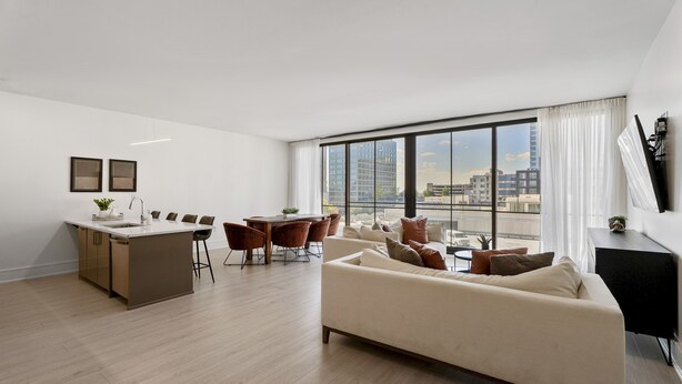 A modern living room with a sofa, dining area, and kitchen.