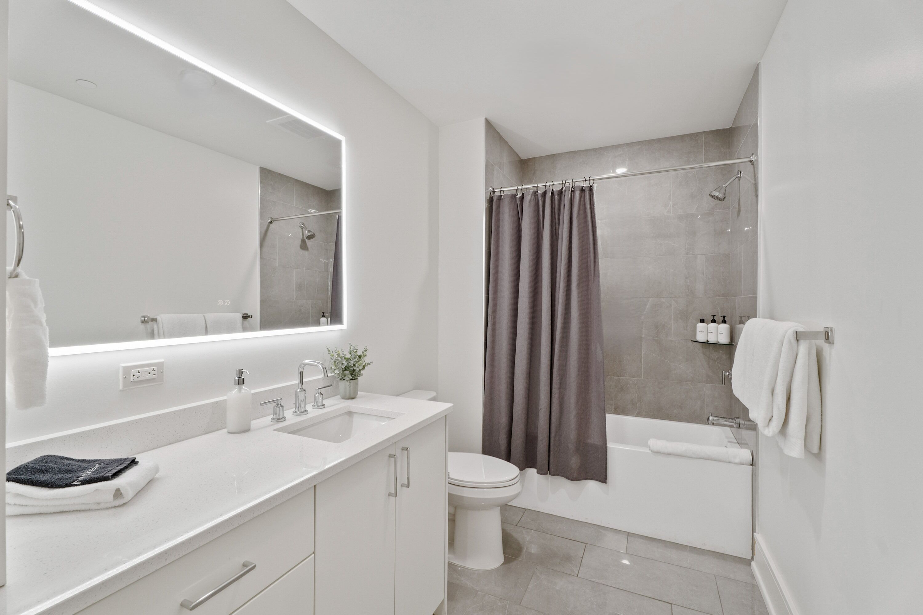 Een moderne badkamer met een witte wastafel, spiegel en toilet.
