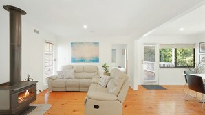 Ein modernes Wohnzimmer mit Kamin, einem beigen Sofa, einem Relaxsessel und einem Essbereich.