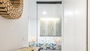 Un dormitorio moderno con cama, mesitas de noche y un espejo grande.