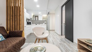 Una sala de estar moderna con un sofá, una silla blanca y una mesa redonda con un plato.
