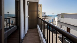 Un balcón con vistas al mar y edificios cercanos.