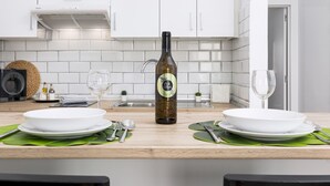 Una cocina moderna con armarios blancos, una botella de vino y dos platos blancos sobre una encimera de madera.