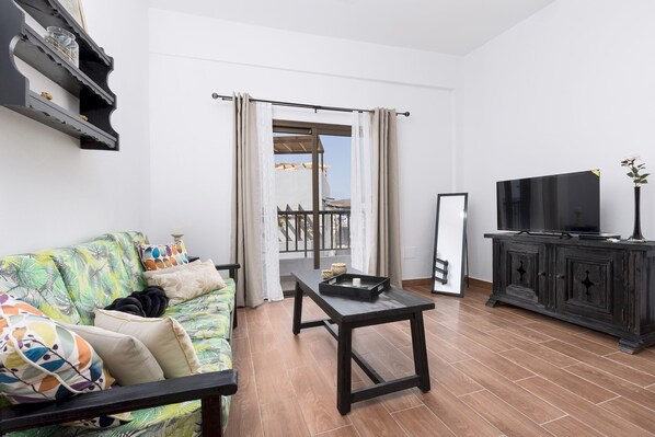 A living room with a sofa, a coffee table, a TV, and a cabinet.