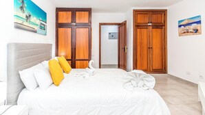 Habitación de hotel con cama, armarios de madera y un cuadro de una playa.