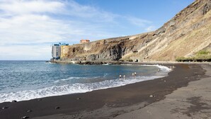 A beach with a rocky cliff and a building on top. - Home2Book Ocean Breeze Terrace Stay, Mesa del Mar (Mesa del Mar)