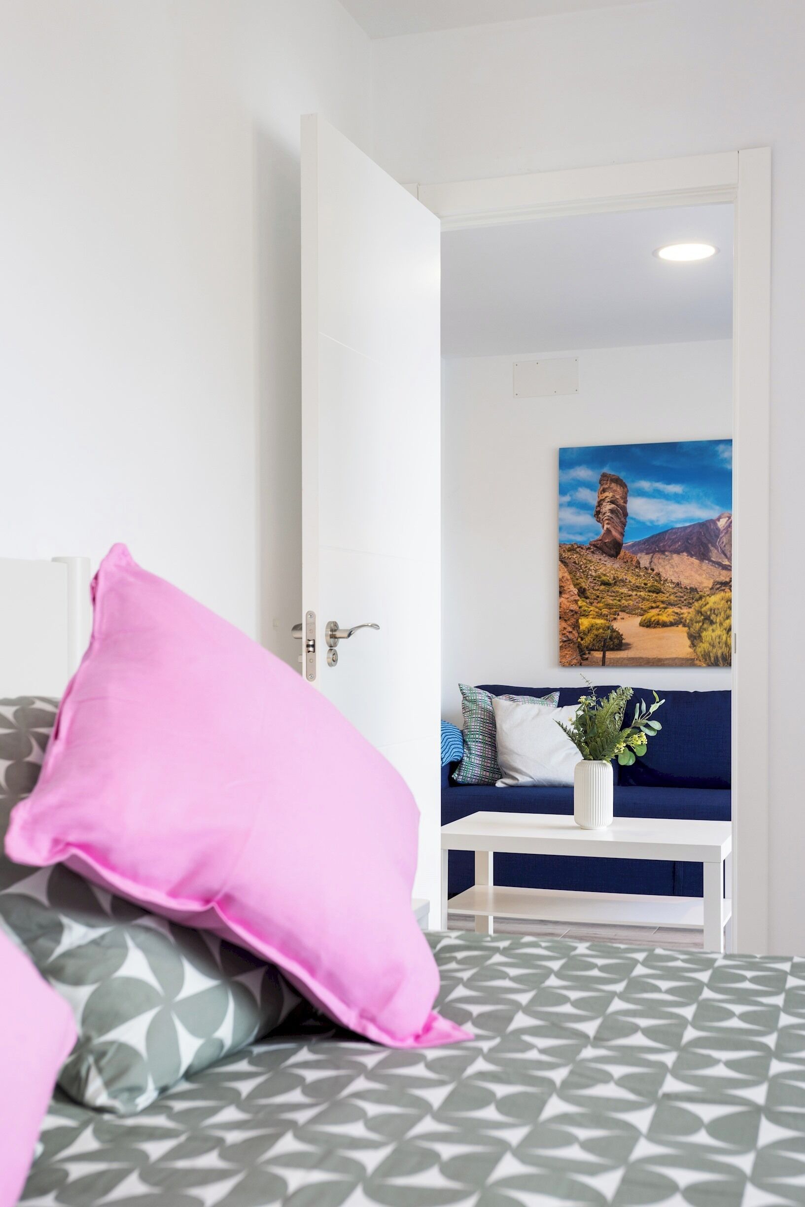 Une chambre à coucher avec un lit, une table de chevet, un tableau et une fenêtre.