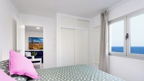 A bedroom with a bed, a window with a view of the sea, a painting on the wall, and a door leading to another room. - Home2Book Ocean Breeze Terrace Stay, Mesa del Mar (Mesa del Mar)