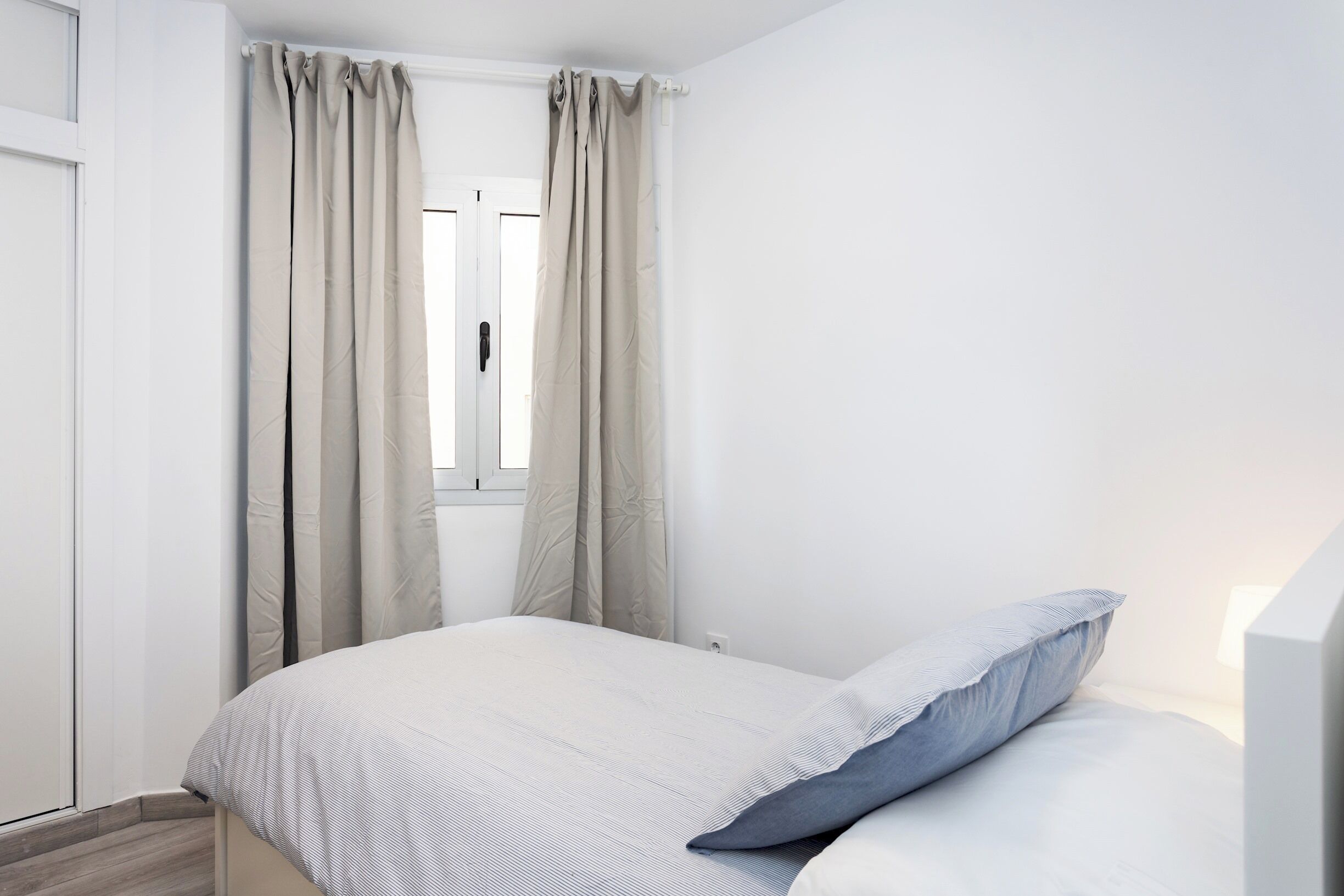 Un dormitorio con cama, cortinas y ventana.