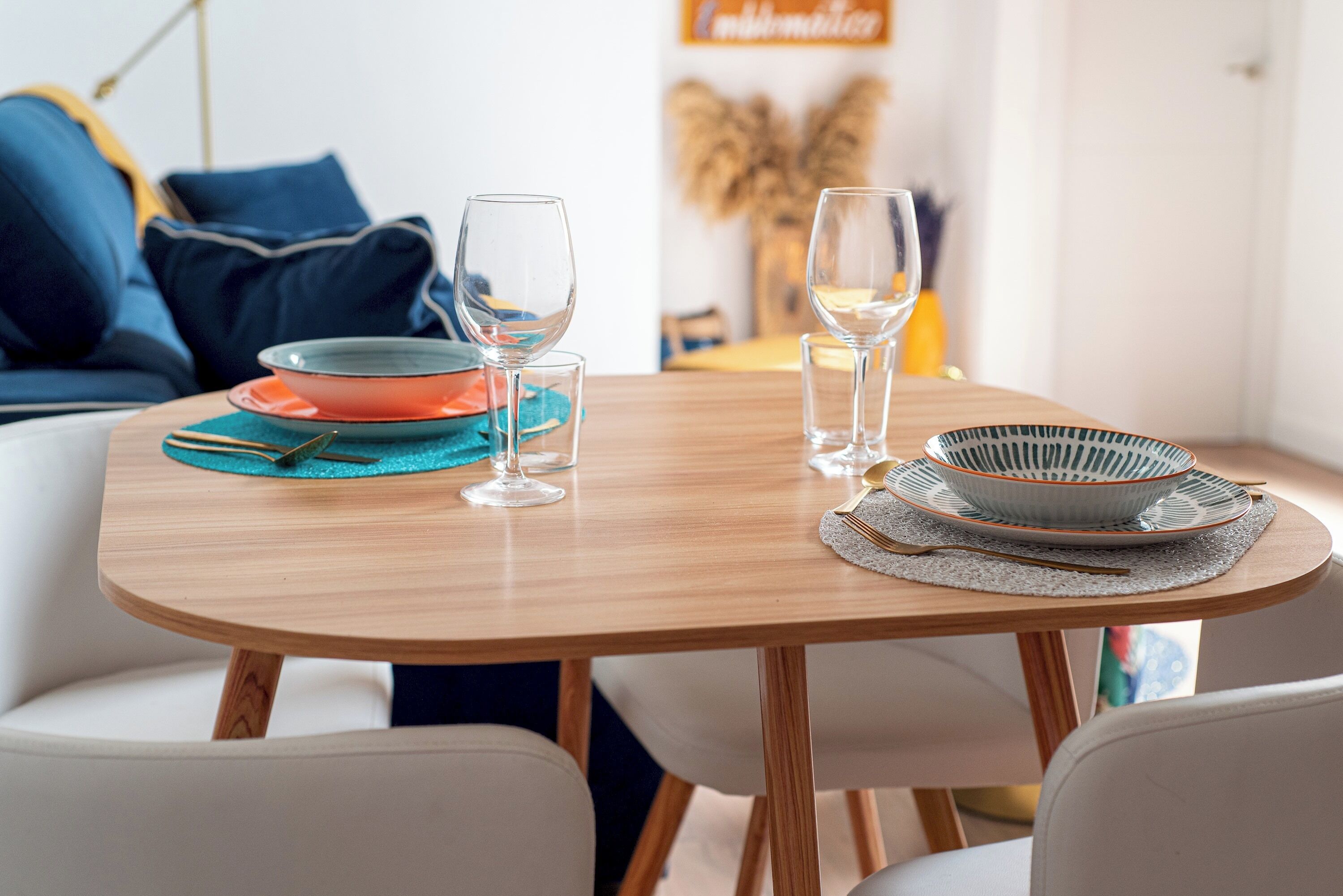 Ein Esstisch mit sauberem Glasgeschirr, bunten Tellern und einer Schüssel, gedeckt für eine Mahlzeit.