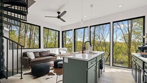 A modern kitchen with a central island, large windows, and a staircase. - Lofty Ledges Hangout at French Broad River Farms (Buncombe County)