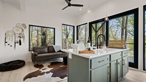 Una cocina moderna con una isla central, ventanas amplias y un ventilador de techo.