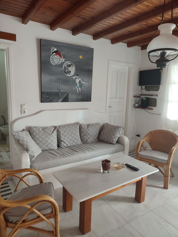 Un salon avec un canapé, deux fauteuils, une table basse et un tableau accroché au mur.