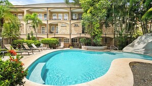 A pool area with lounge chairs and a multi-story building with balconies. - Villa Verde 1#8 (Tamarindo)
