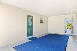 Una habitación con alfombra azul, puerta verde y pared blanca.