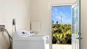 A laundry room with a washing machine, a dryer, and a door leading to a patio with plants. - Charming Villa 14 mins away from Siesta Key Beach (Sarasota)