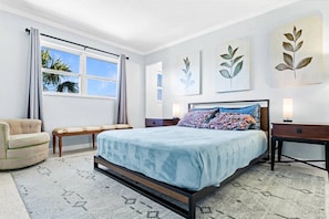A bedroom with a bed, a chair, a desk, and a window with curtains.