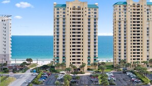 A high-rise hotel with multiple floors, a parking lot, and a view of the ocean. - Beach Colony East 1B (Pensacola)