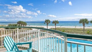 A balcony with a pool, overlooking a beach with palm trees and the ocean. - Beach Colony East 1B (Pensacola)