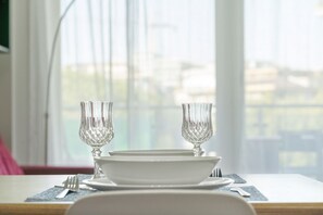 A dining table set with white plates, two clear glassware, and a fork and knife on a placemat. - Green park apartment (Roma)