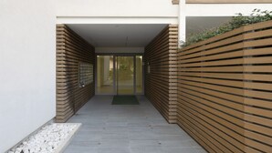 A narrow corridor with a wooden slatted wall on one side and a glass door entrance.