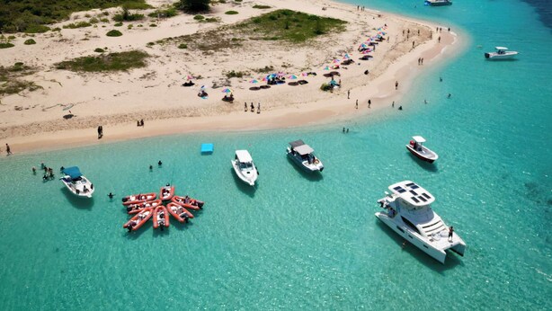 A beach with boats docked and people sunbathing.